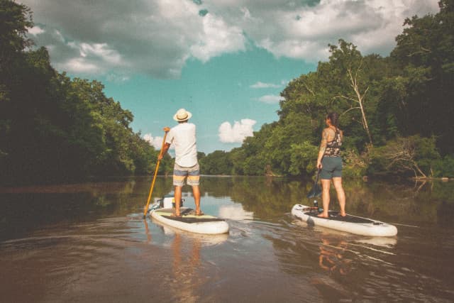 two people paddle boarding on the French Broad River right through West Asheville two people paddle boarding on the French Broad River right through West Asheville
